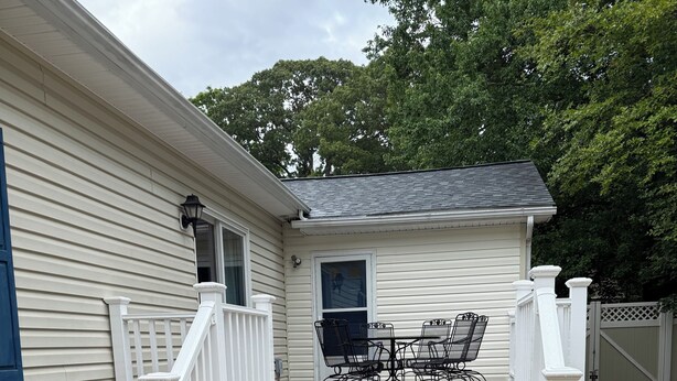 A covered patio with a table and chairs, a white railing, and a gravel ground. - Quiet neighborhood/ pets friendly? fenced in / close to beach (Rehoboth Beach)