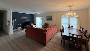 A living room with a red sofa, a dining table with chairs, a chandelier, and a TV. - Quiet neighborhood/ pets friendly? fenced in / close to beach (Rehoboth Beach)