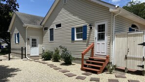A two-story house with a gravel driveway and a wooden staircase leading to the front door. - Quiet neighborhood/ pets friendly? fenced in / close to beach (Rehoboth Beach)