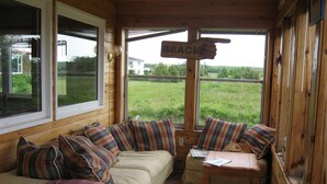En mysig stuga med en soffa, ett litet bord och en skylt som visar vägen till stranden.