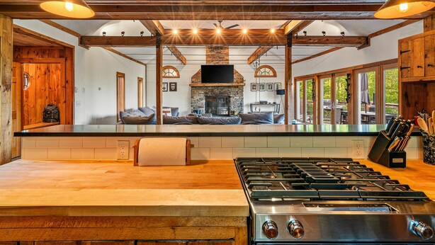 Una cocina amplia con una isla grande, una chimenea de piedra y vigas de madera.