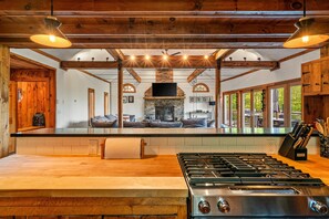 Una cocina amplia con una isla grande, una chimenea de piedra y vigas de madera.