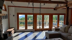 Una habitación amplia con ventanas grandes, techo de madera y pared de piedra.