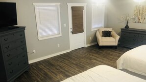 Une chambre avec deux lits, une commode, une chaise et un téléviseur.