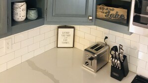 A kitchen with blue cabinets, white tiles, a toaster, and various decorative items.