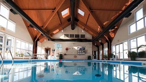 Una piscina interior con techos altos y ventanas amplias.