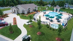 Un resort con una piscina grande, sillas de descanso y un césped bien cuidado.