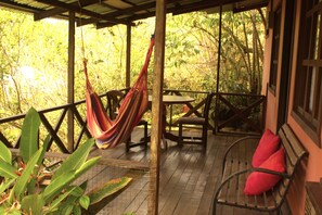 A wooden deck with a hammock, a table, and chairs. - Cabañas Colibrí Tayutic (Turrialba)