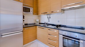 Une cuisine moderne avec des meubles en bois, des appareils électroménagers en acier inoxydable et un plan de travail noir.