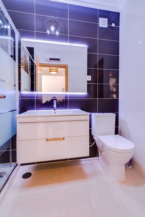 A modern bathroom with a white vanity, a mirror, and a toilet.