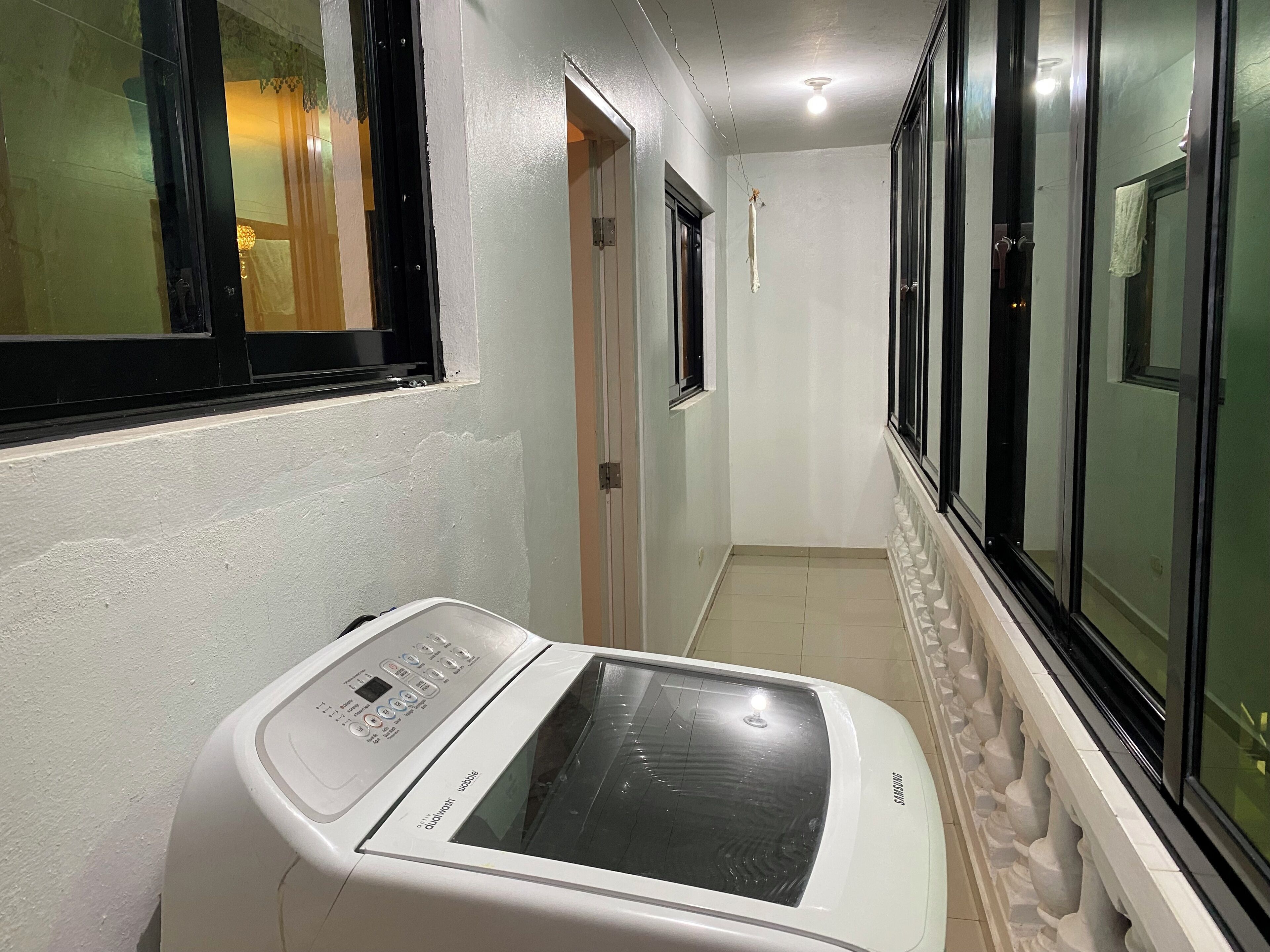 Ein Waschraum mit einer Waschmaschine mit Frontlader, einem Fenster und einer Tür.