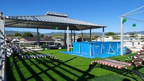 An outdoor obstacle course with artificial grass, a covered area, and a blue tarp.