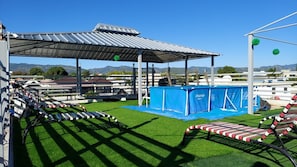 Un parcours d’obstacles en plein air avec une surface en gazon synthétique, un espace abrité et une bâche bleue.