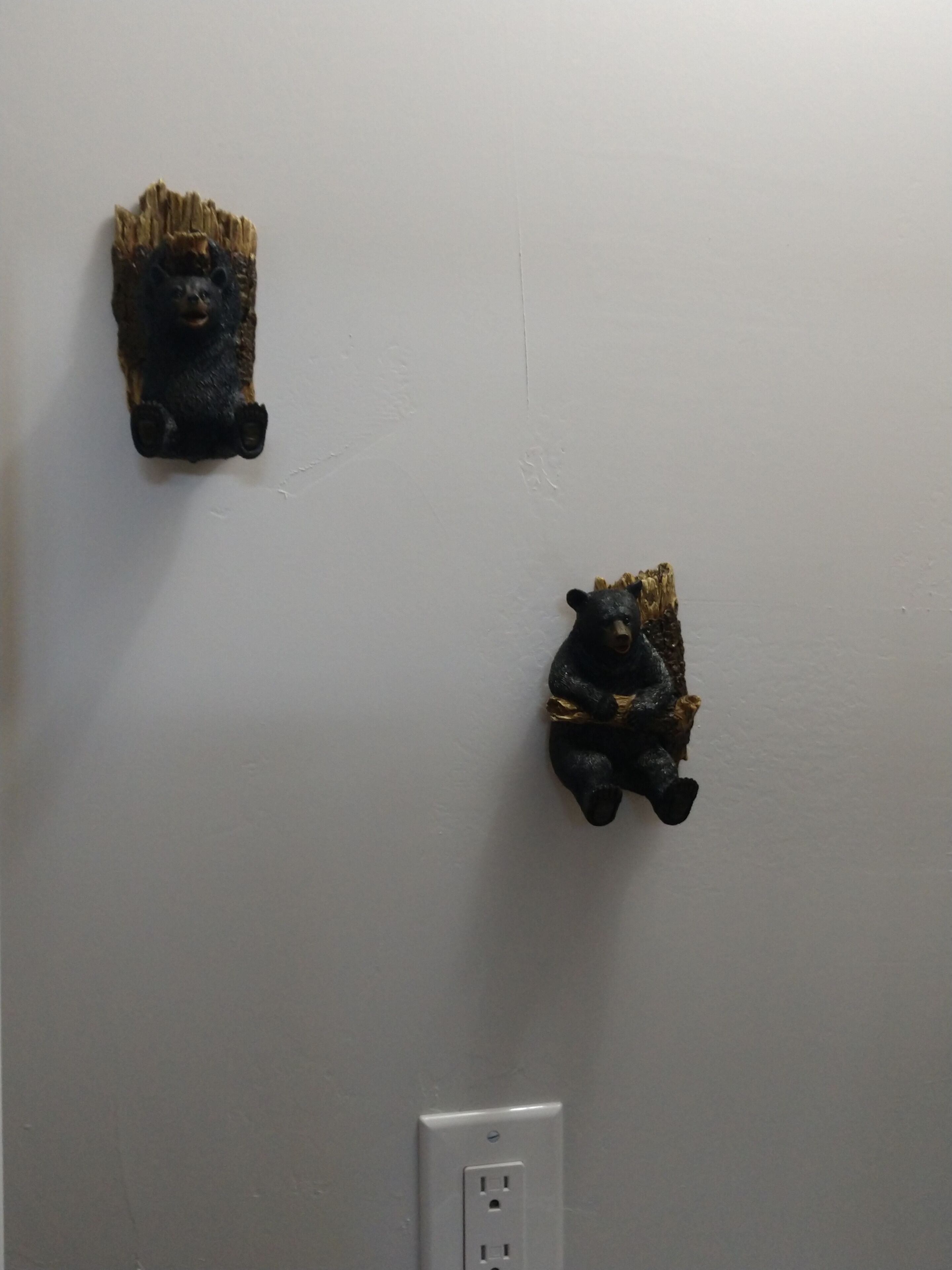 Dos esculturas de osos montadas en la pared, con un enchufe debajo.