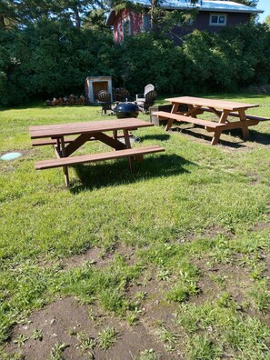 A grassy outdoor area with picnic tables and a barbecue grill. - Beautiful cabin close to Glacier Park, Flathead Lake & Whitefish Mountain. (Columbia Falls)