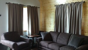 Un salon chaleureux avec un canapé en cuir marron, un fauteuil marron et un plafond en bois.