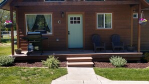 Une cabane en bois avec un porche à l’avant, une porte et deux fenêtres.