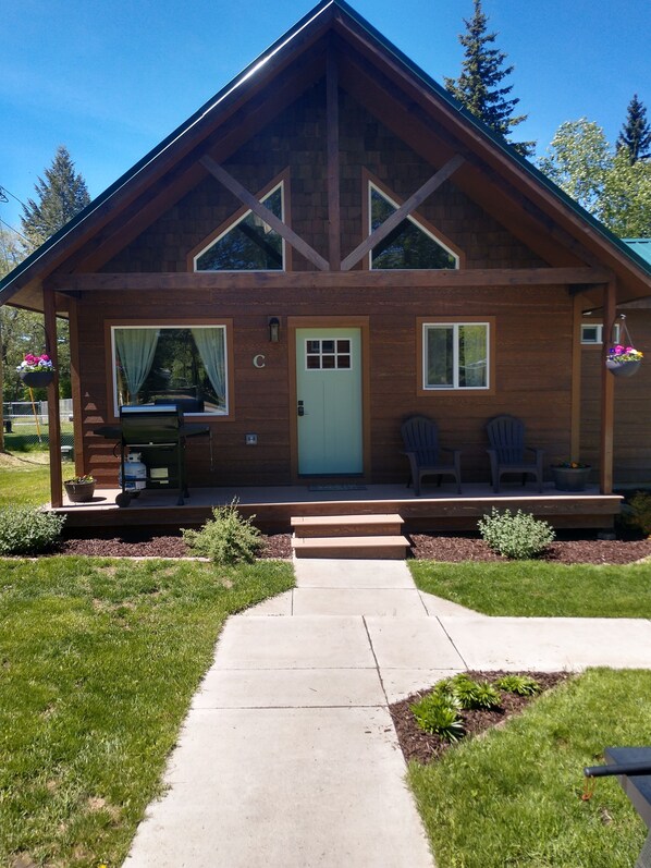 A wooden cabin with a front porch, a door, and two windows. - Beautiful cabin close to Glacier Park, Flathead Lake & Whitefish Mountain. (Columbia Falls)