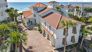 Propiedad costera con varias construcciones, piscina y palmeras.