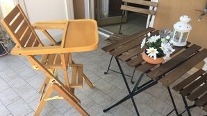 A wooden chair and table set on a tiled floor, with a potted plant and a lantern on the table. - Island 92100: beautiful house in the heart of Agrigento (Agrigento)