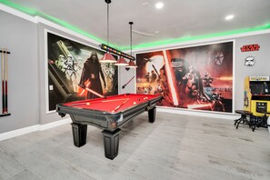 A pool table in a room with Star Wars-themed wall art and a pool table.