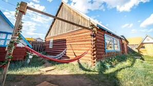 A wooden log cabin with a hammock in the yard. - Mountain View Guesthouse (Moron)