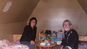 A small, cozy attic room with two bunk beds, a small round table with various items, and a wooden ceiling. - Mountain View Guesthouse (Moron)