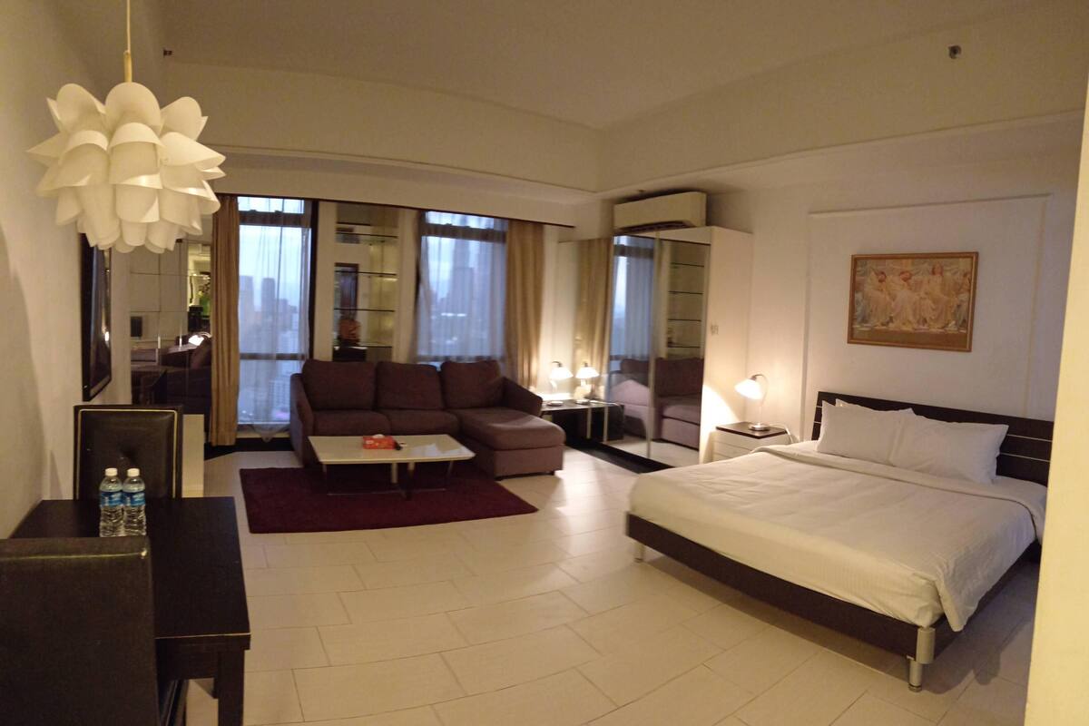 Une chambre d’hôtel avec un lit, un canapé, un bureau et une grande fenêtre.
