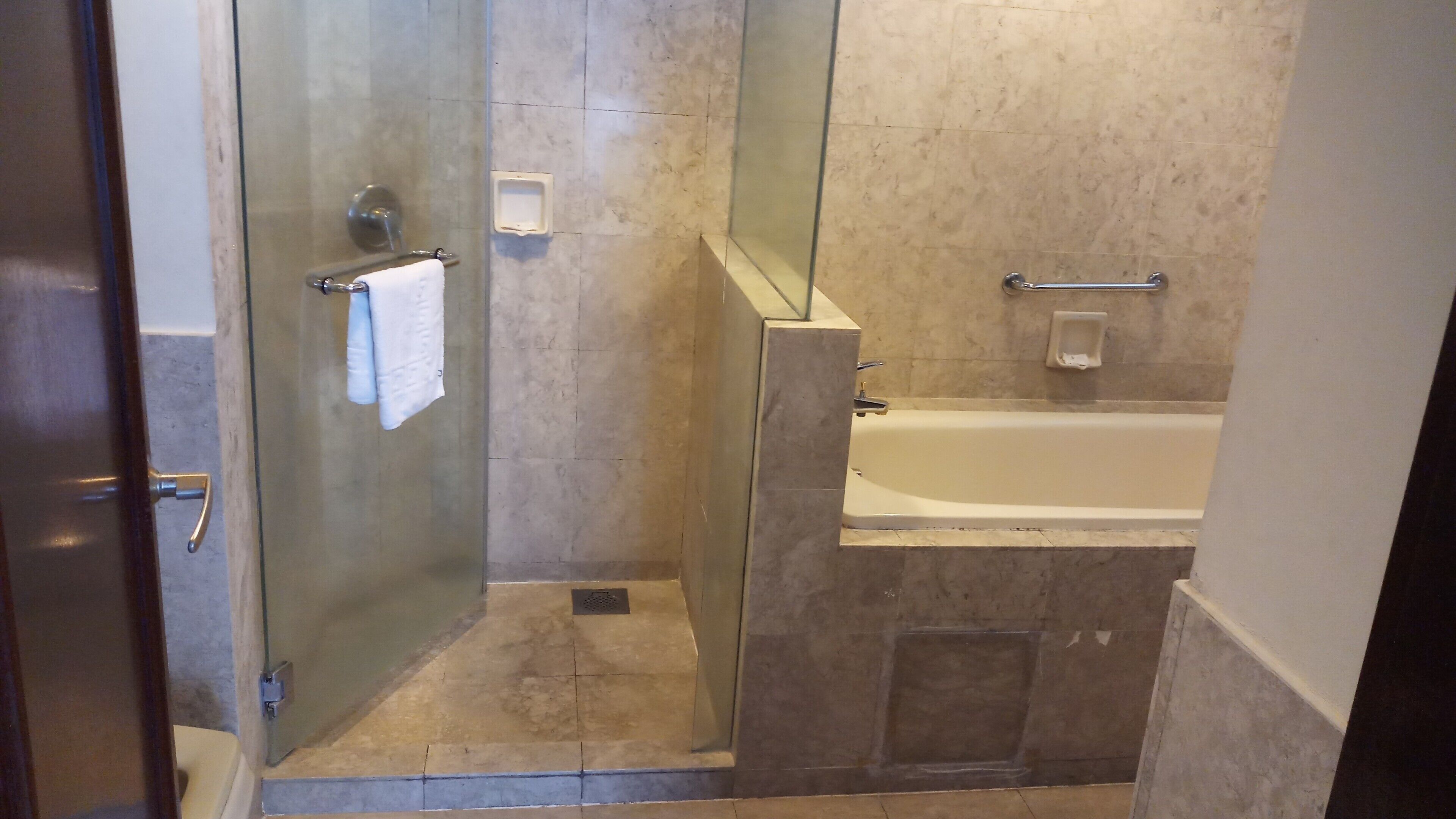 A bathroom with a glass-enclosed shower, a bathtub, and a towel rack.