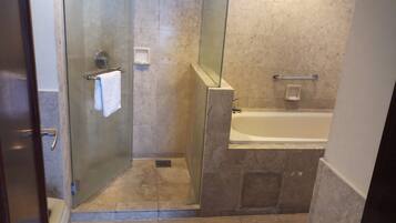 A bathroom with a glass-enclosed shower, a bathtub, and a towel rack.