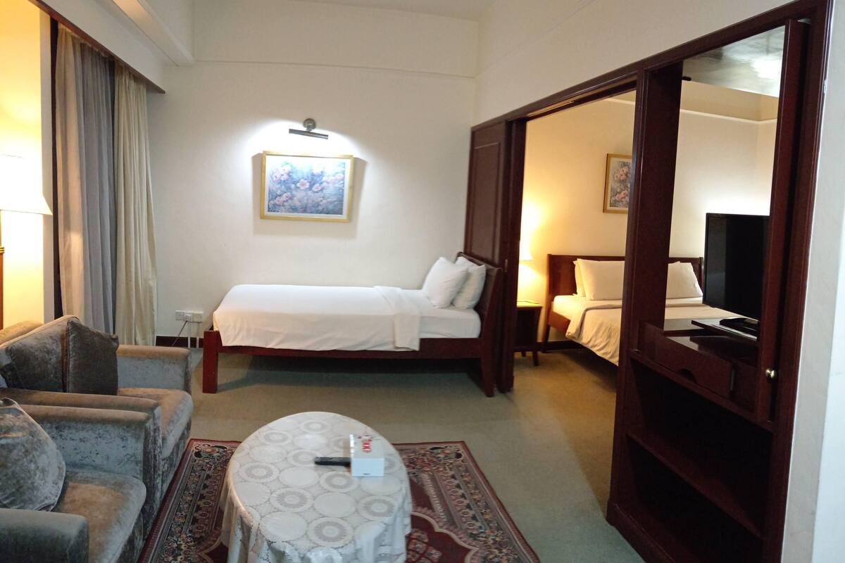 Une chambre d’hôtel avec un lit, un canapé, une petite table et un téléviseur.