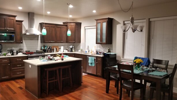 A modern kitchen with wooden cabinets, a central island with stools, a dining table with chairs, and a chandelier. - Beautiful home close to the Eugene Airport with easy access to downtown Eugene (Eugene)