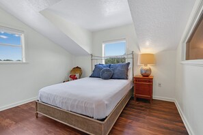 A bedroom with a bed, a nightstand, a lamp, and two windows. - Mi Rancho- 2 bed/2 bath-Hot tub, Fire pit, and Pinball machine! (Wimberley)