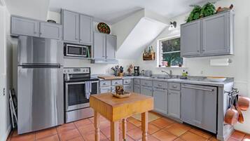 Une cuisine moderne avec des meubles gris, des appareils en acier inoxydable et une table en bois.