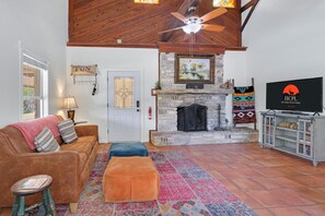 Una sala de estar acogedora con chimenea de piedra, un televisor y un espacio de descanso cómodo.