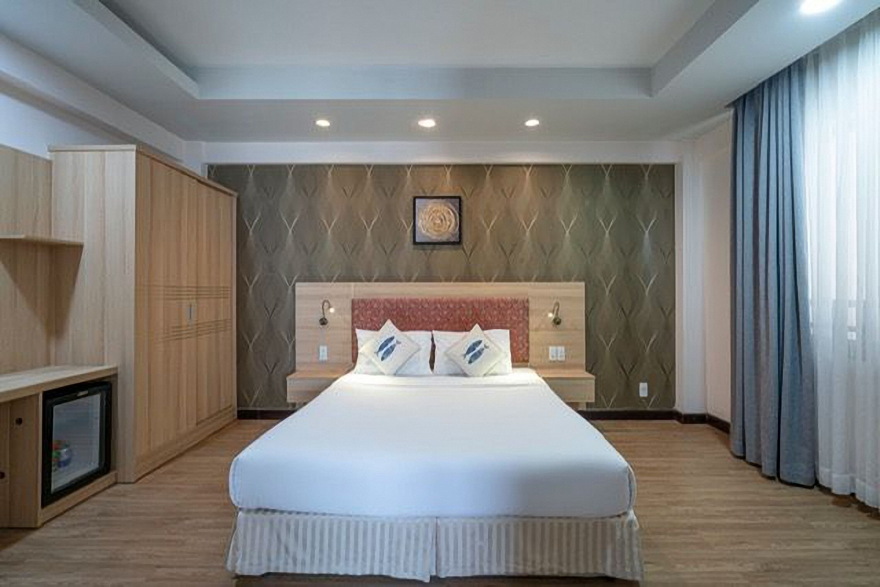 Habitación de hotel con una cama grande, un armario de madera y un televisor pequeño.
