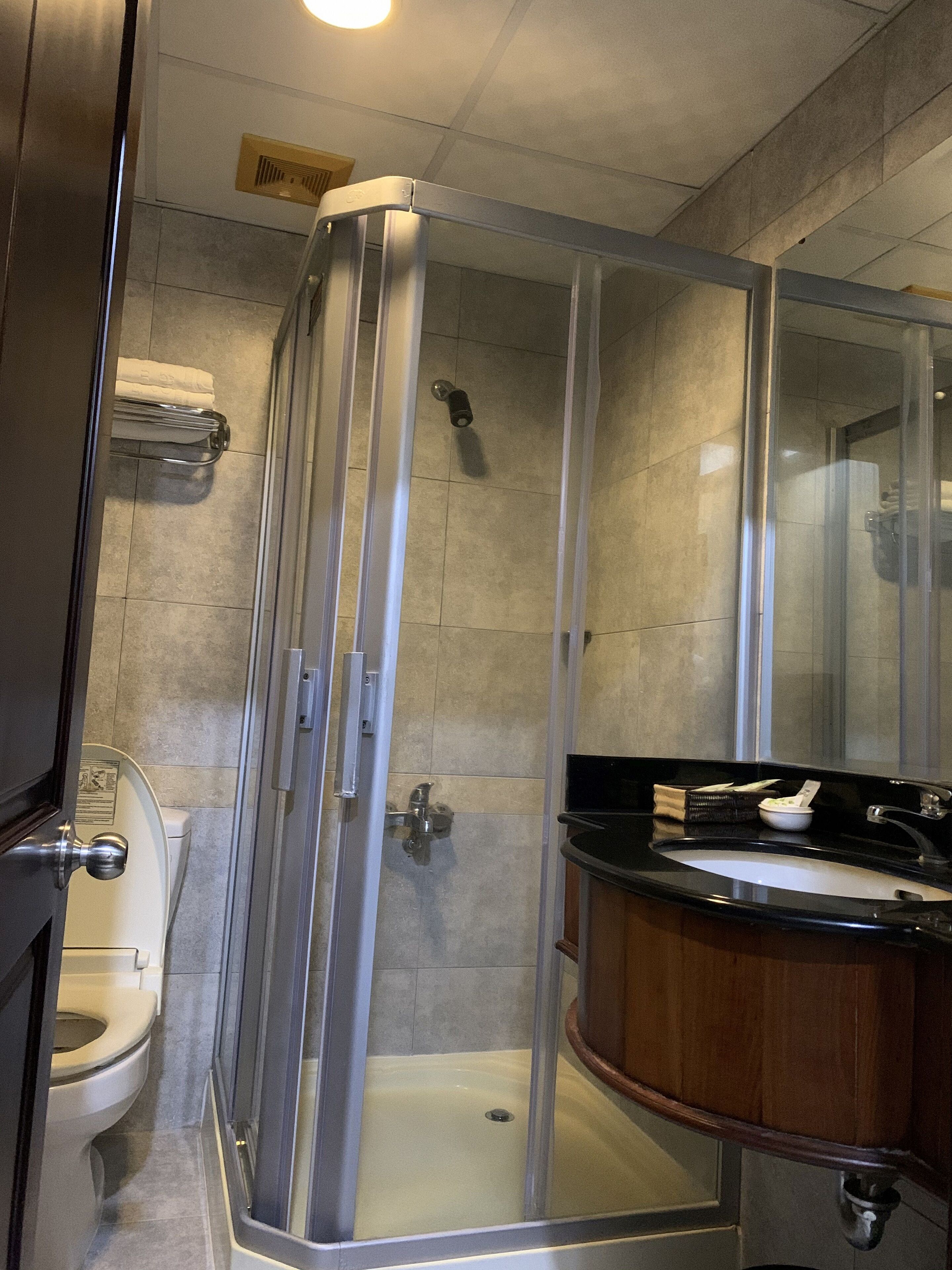 A modern bathroom with a glass-enclosed shower, a toilet, and a sink with a black countertop.