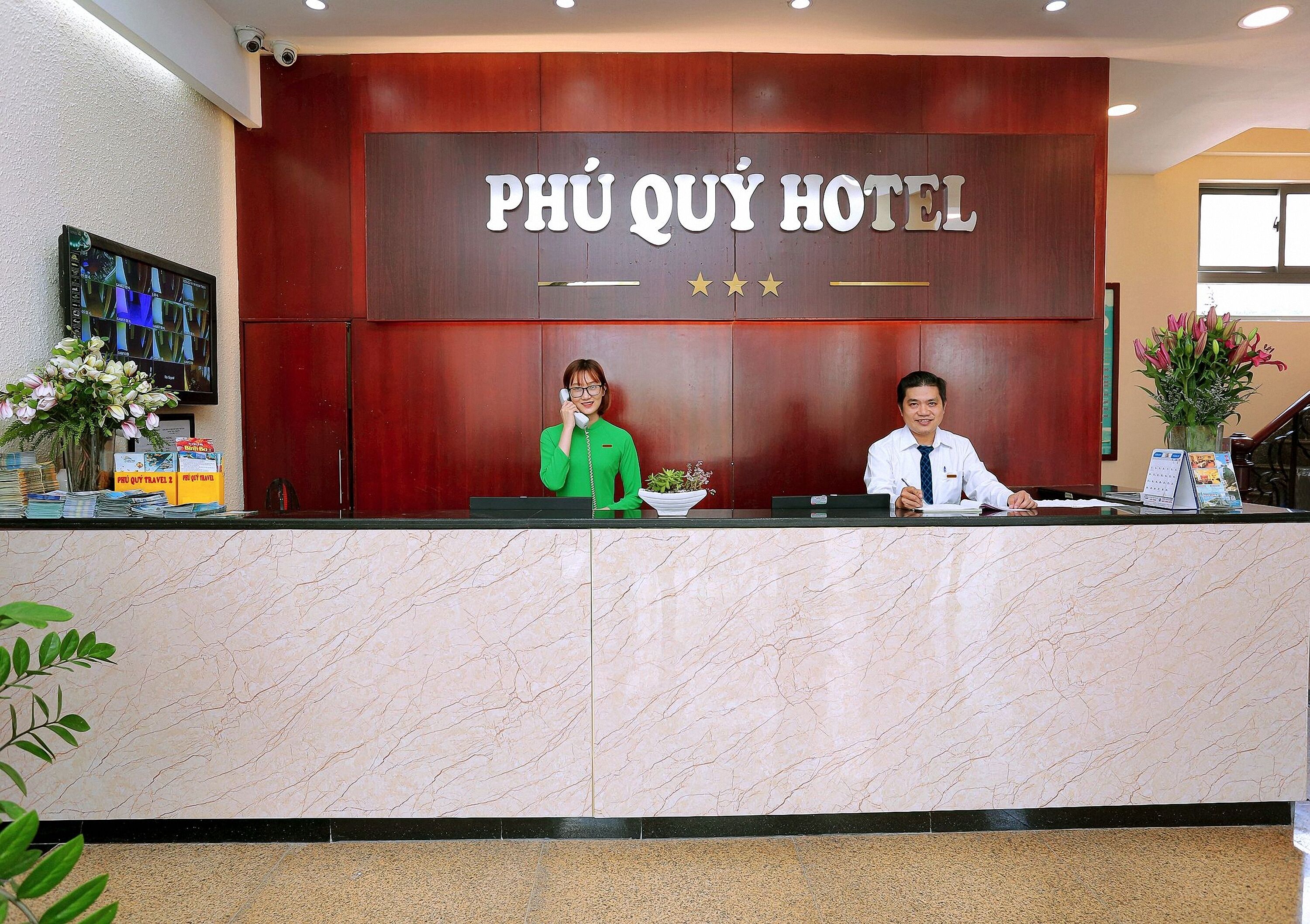 A reception desk at Phú Quý Hotel with a wooden backdrop and a marble counter.