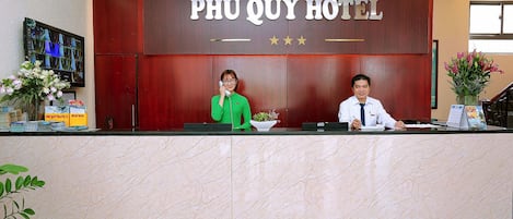 A reception desk at Phú Quý Hotel with a wooden backdrop and a marble counter.