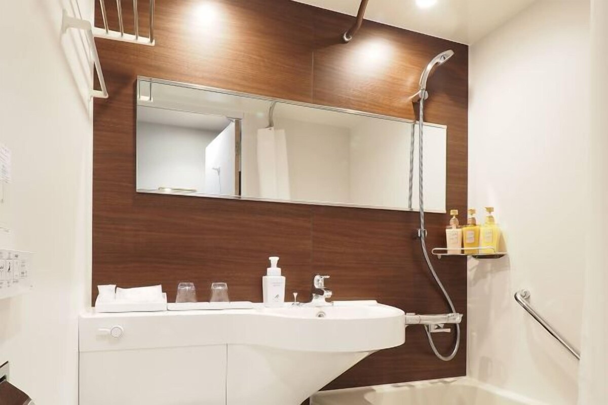A bathroom with a white sink, a mirror, and a shower.