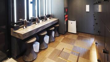 A modern restroom with a long vanity, multiple sinks, and a trash bin.