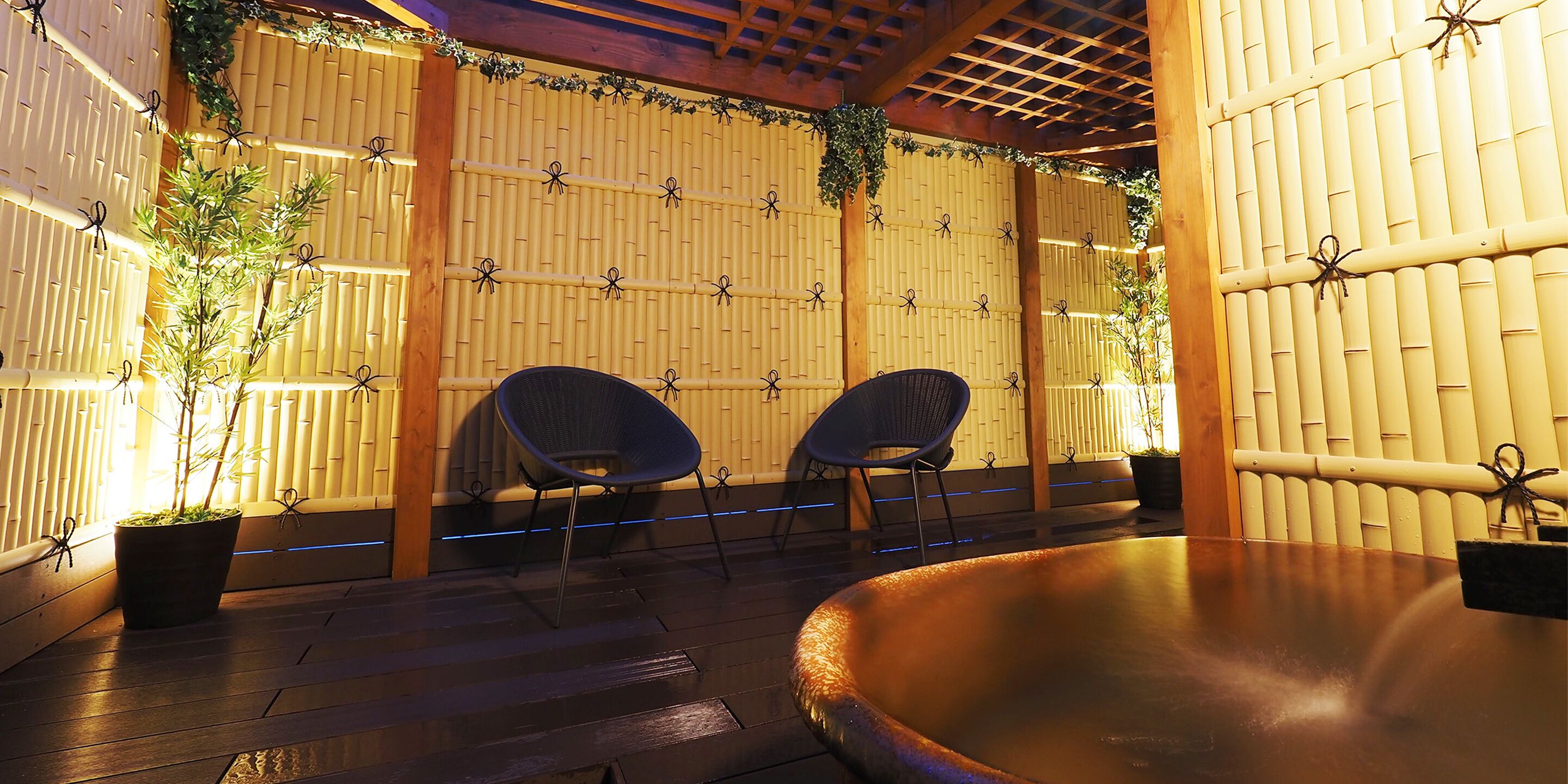 An outdoor seating area with bamboo walls, two chairs, and a round table.