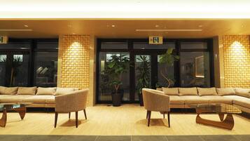 A modern lobby with a sectional sofa, two armchairs, and a glass coffee table.
