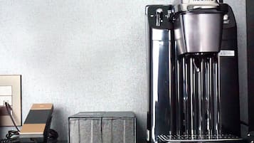 A coffee machine with a water reservoir and a drip tray, connected to a power outlet.