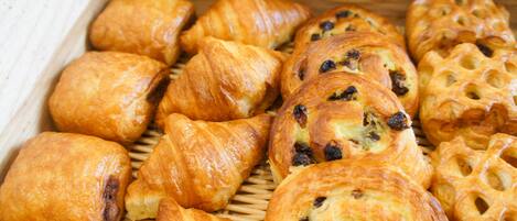 A variety of pastries, including croissants and filled pastries, arranged on a wooden surface.