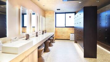 A modern restroom with a long vanity, multiple sinks, and a row of lockers.