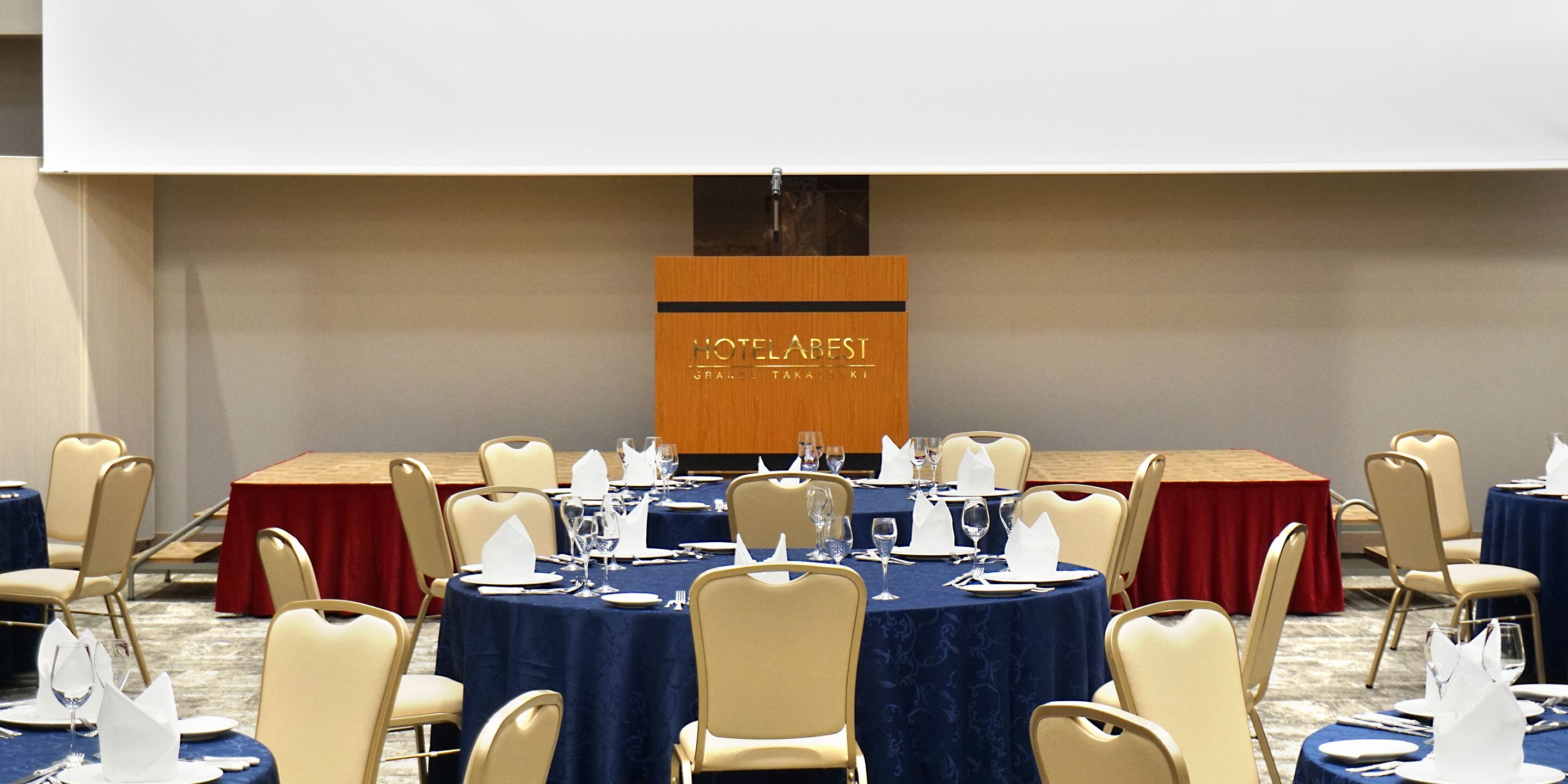 A conference room with round tables, chairs, and a podium.