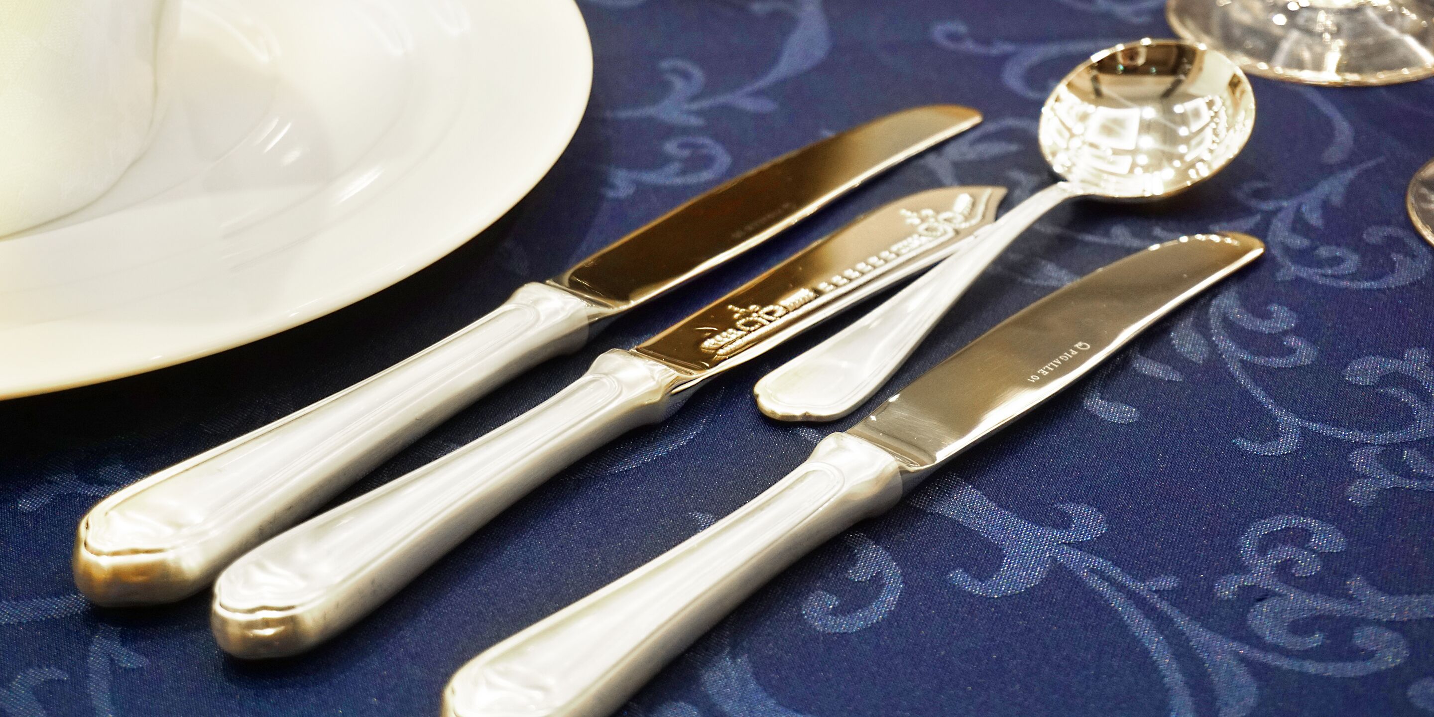 Cubiertos sobre un mantel azul con un plato blanco.