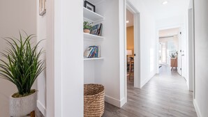 A hallway with a bookshelf, a potted plant, and a woven basket.