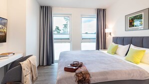 Een moderne hotelkamer met een groot bed, een bureau en uitzicht op het buitenlands landschap door de ramen.